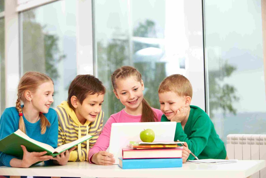 Group of children looking to laptop in classroom
